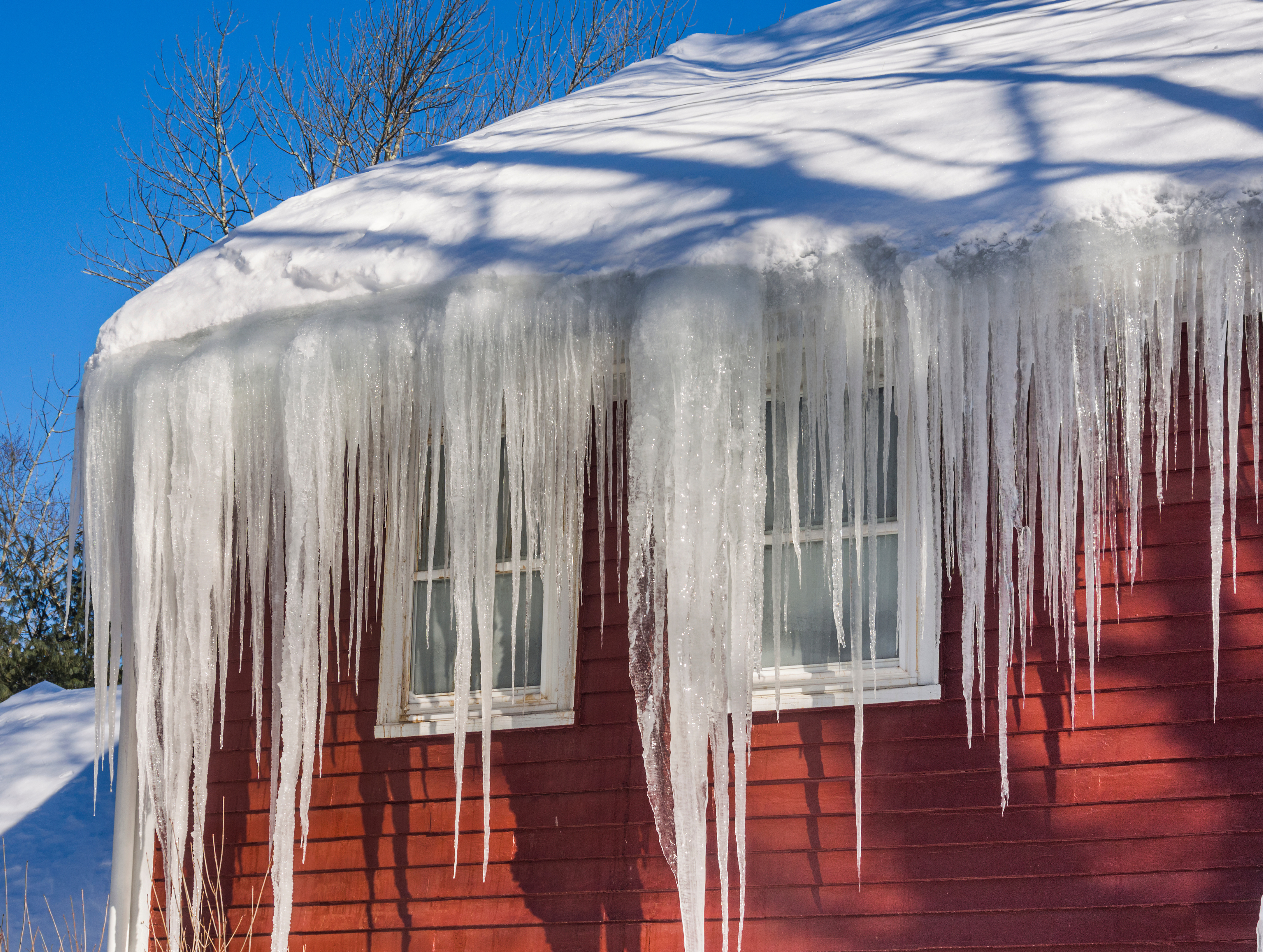 red house with lots of snow on roof and icicles